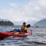 Chad Sayers paddling a kayak in Chile with his skis strapped to the side and another kayaker in the background