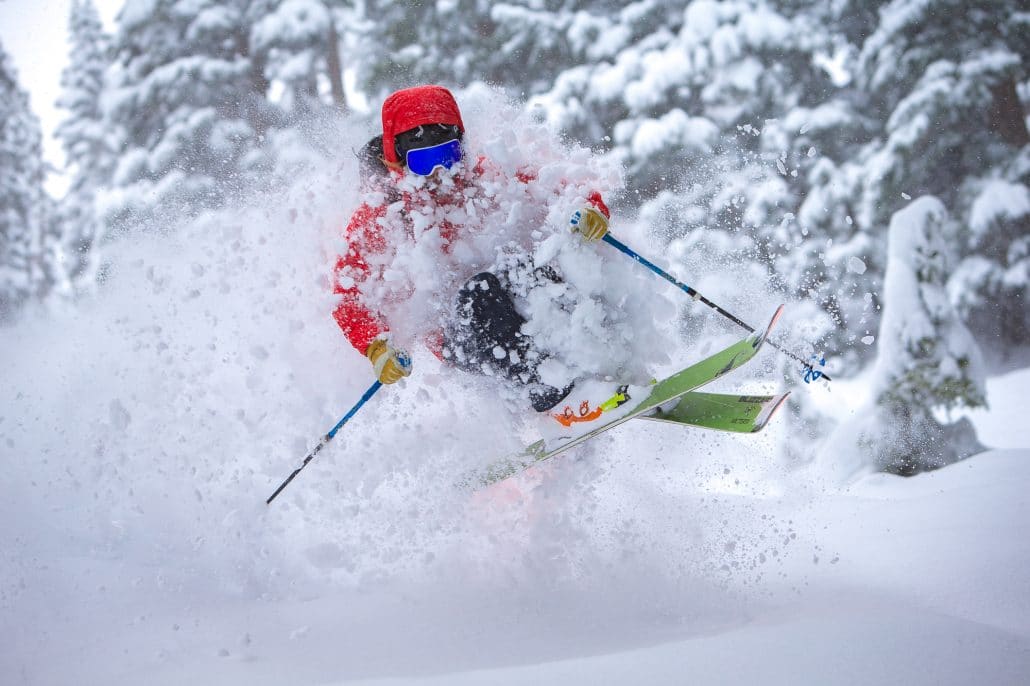 Heli skier catching air in the powder on some Blizzard Rustler 11 skis.
